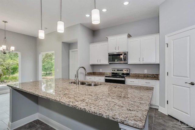 kitchen featuring a kitchen island with sink, hanging light fixtures, stainless steel appliances, sink, and white cabinets