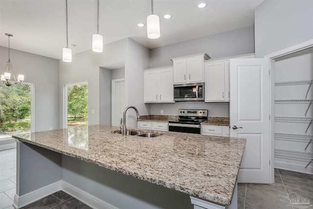 kitchen with appliances with stainless steel finishes, sink, decorative light fixtures, white cabinets, and a kitchen island with sink