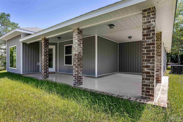 view of exterior entry with a yard and central AC