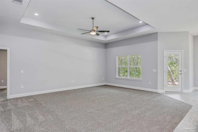 carpeted spare room with ceiling fan and a raised ceiling