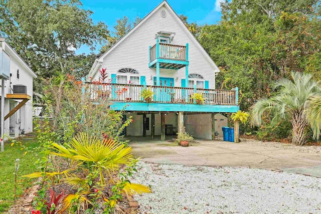 back of property with a carport, central AC unit, and a balcony