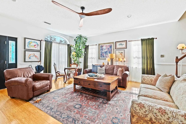 living room featuring a textured ceiling, light hardwood / wood-style flooring, and ceiling fan