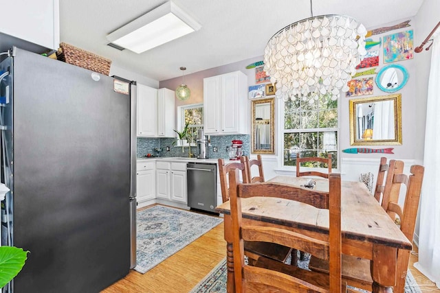 kitchen featuring a wealth of natural light, white cabinets, hanging light fixtures, and appliances with stainless steel finishes