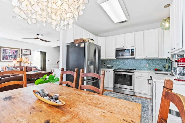 kitchen featuring appliances with stainless steel finishes, tasteful backsplash, ceiling fan, decorative light fixtures, and white cabinetry