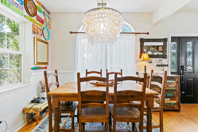 dining space with hardwood / wood-style floors, an inviting chandelier, and beam ceiling