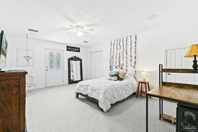 carpeted bedroom featuring ceiling fan and a textured ceiling