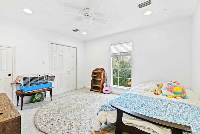 carpeted bedroom with ceiling fan, a closet, and a textured ceiling