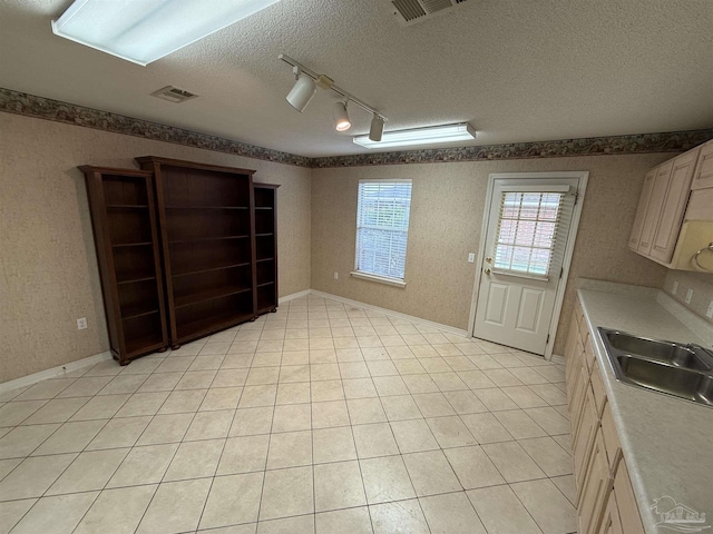 interior space with a textured ceiling, baseboards, visible vents, and a sink