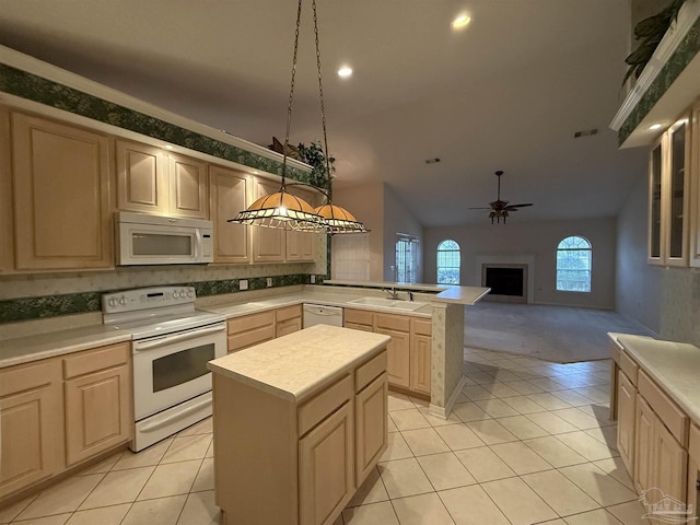 kitchen featuring white appliances, a peninsula, light countertops, and a sink