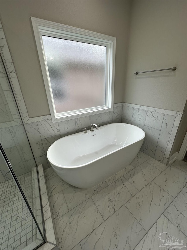 bathroom featuring a washtub and tile walls