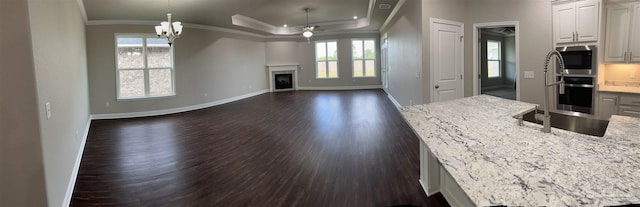 kitchen featuring decorative light fixtures, built in microwave, white cabinets, a tray ceiling, and crown molding