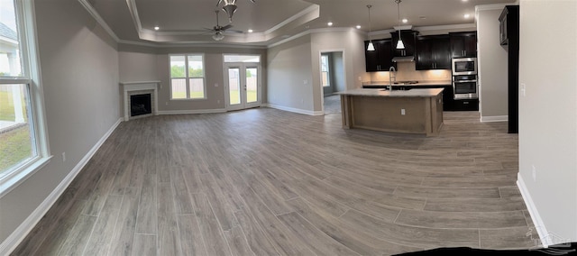 unfurnished living room with ceiling fan, ornamental molding, dark hardwood / wood-style floors, and a raised ceiling