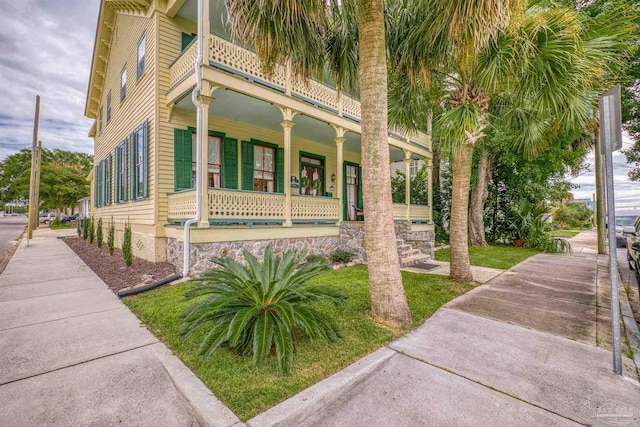 view of side of property with a balcony and covered porch