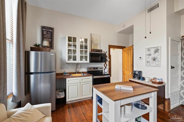 kitchen with white cabinets, sink, butcher block countertops, dark wood-type flooring, and stainless steel appliances