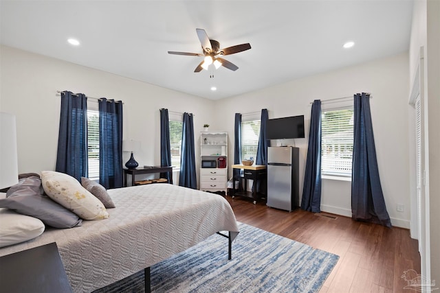 bedroom with ceiling fan, dark wood-type flooring, and stainless steel fridge