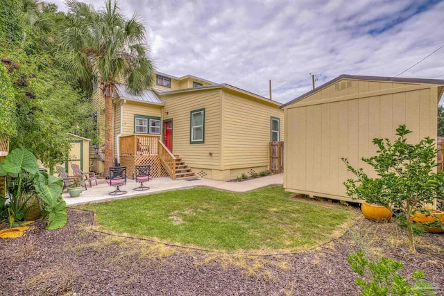 rear view of house with a storage unit, a yard, and a patio