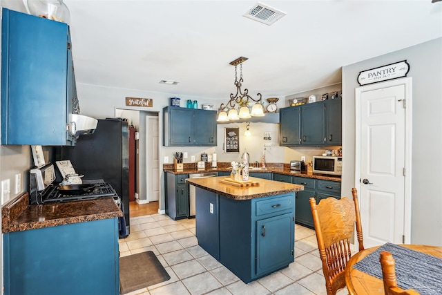 kitchen with blue cabinets, dark countertops, and white microwave