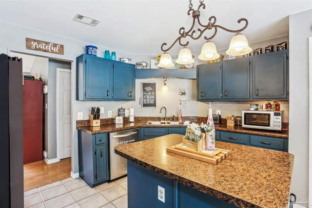 kitchen featuring a sink, light tile patterned flooring, stainless steel appliances, blue cabinetry, and visible vents