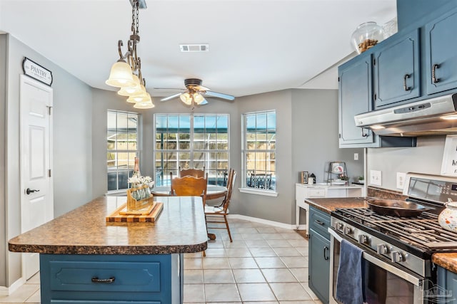 kitchen with blue cabinets, stainless steel range with gas stovetop, dark countertops, a ceiling fan, and under cabinet range hood