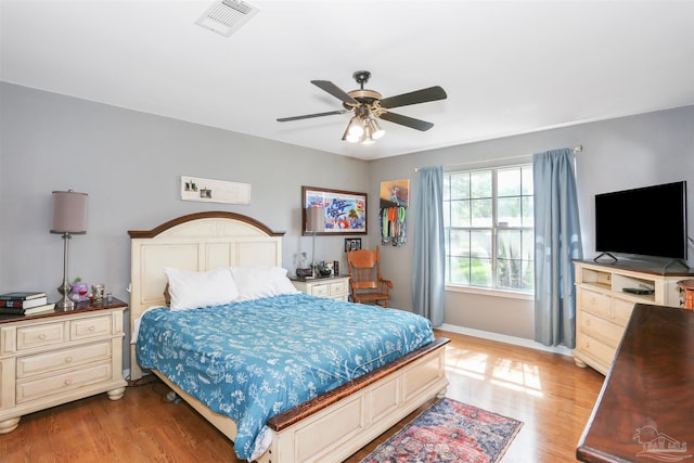 bedroom featuring baseboards, light wood-style flooring, visible vents, and ceiling fan