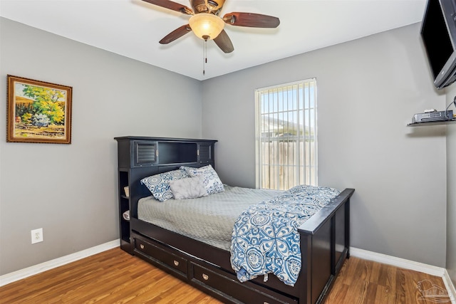 bedroom featuring wood finished floors, baseboards, and a ceiling fan
