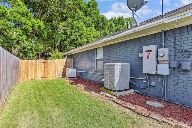 view of side of property featuring central air condition unit, brick siding, a yard, and a fenced backyard