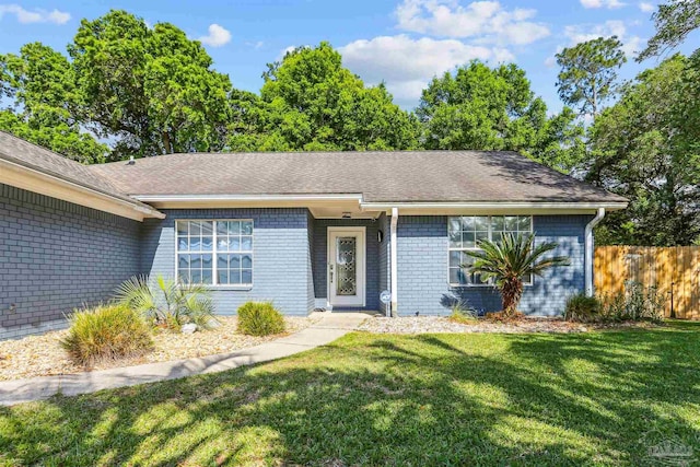 single story home with a front lawn, brick siding, and fence