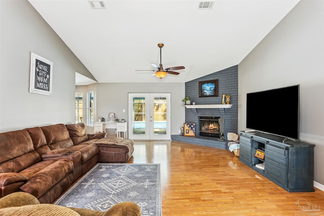 living area featuring wood finished floors, vaulted ceiling, visible vents, and a ceiling fan