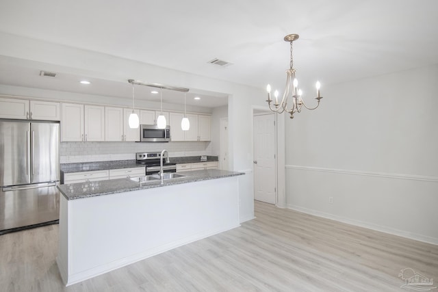 kitchen featuring stainless steel appliances, sink, hanging light fixtures, and backsplash