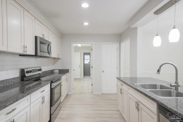 kitchen with white cabinetry, sink, stainless steel appliances, and hanging light fixtures