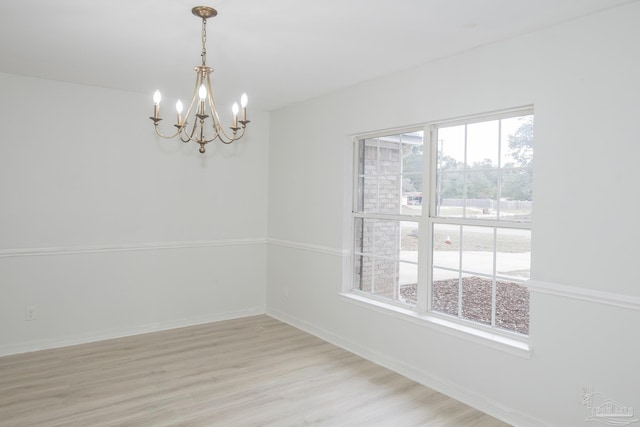 unfurnished room with a chandelier and light hardwood / wood-style floors