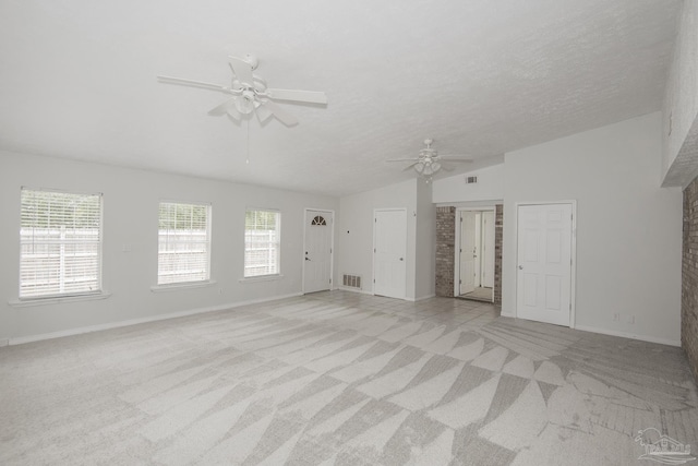 unfurnished living room featuring ceiling fan, light colored carpet, vaulted ceiling, and a textured ceiling