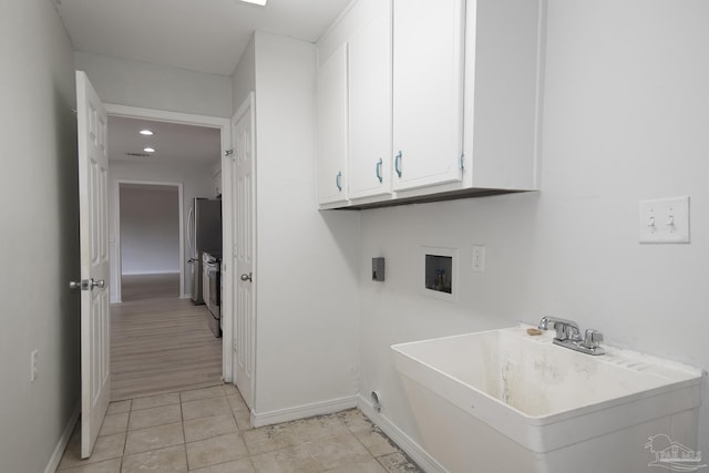 laundry area with cabinets, light tile patterned flooring, sink, and washer / clothes dryer