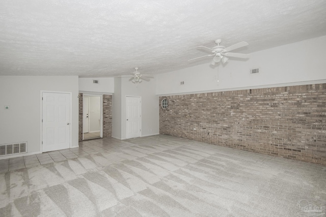 unfurnished room with vaulted ceiling, brick wall, light colored carpet, ceiling fan, and a textured ceiling