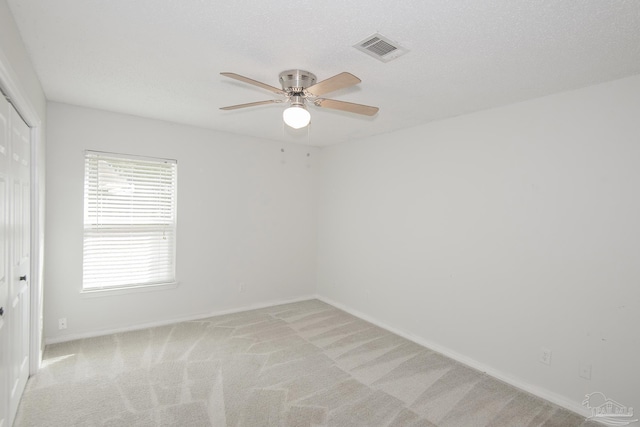 carpeted spare room with ceiling fan and a textured ceiling