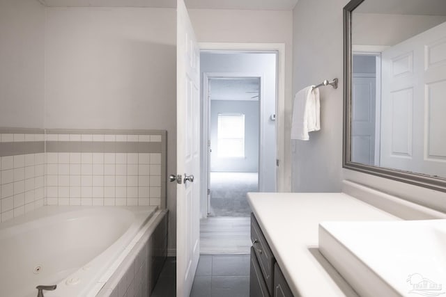 bathroom with a relaxing tiled tub, tile patterned floors, and vanity