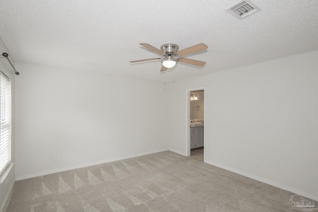 empty room featuring ceiling fan, light colored carpet, and a textured ceiling