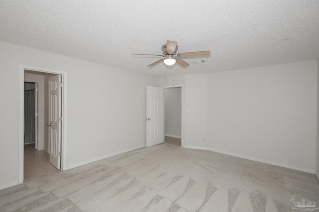 carpeted empty room with ceiling fan and a textured ceiling