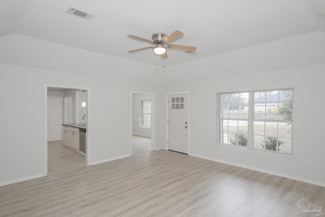 unfurnished living room featuring ceiling fan, a raised ceiling, sink, and light wood-type flooring