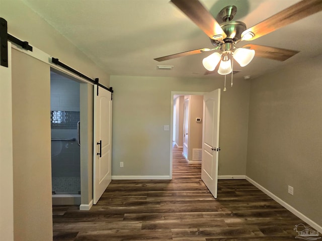 unfurnished room with ceiling fan, wood-type flooring, and a barn door