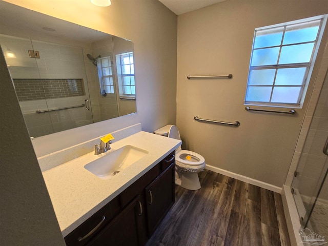 bathroom featuring hardwood / wood-style floors, a shower with door, toilet, and vanity