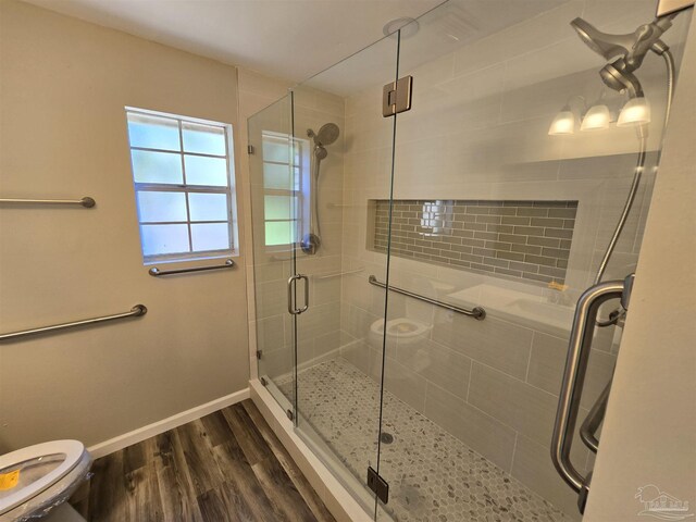 bathroom featuring a shower with door, hardwood / wood-style flooring, and toilet