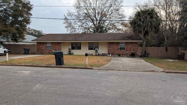 single story home featuring brick siding, fence, and a front lawn