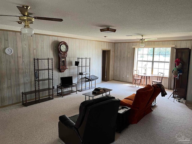 living room featuring ceiling fan, carpet floors, a textured ceiling, and wooden walls