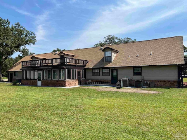 back of house featuring a lawn, a sunroom, a balcony, and central AC