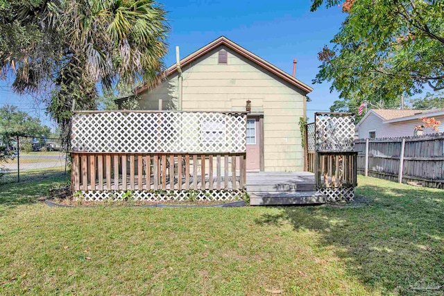 rear view of property with a deck and a lawn