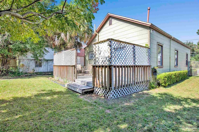 back of house with a wooden deck and a lawn