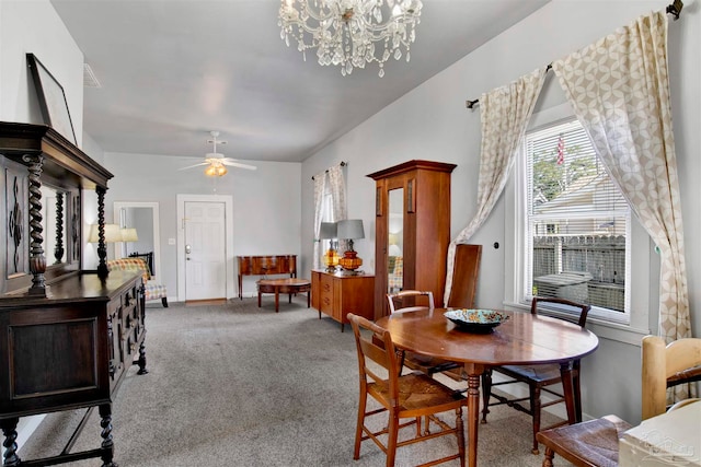 carpeted dining area featuring ceiling fan with notable chandelier