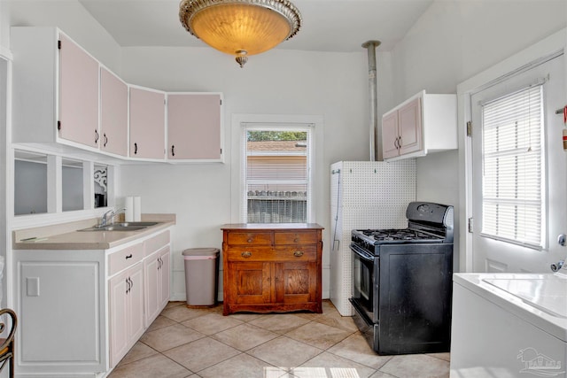 kitchen featuring white cabinets, gas stove, a healthy amount of sunlight, and washer / clothes dryer