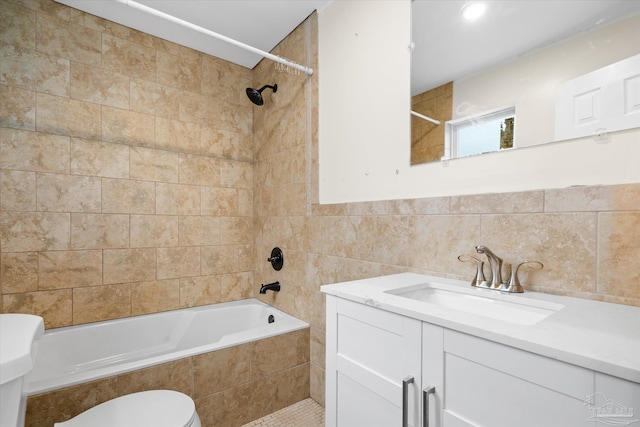 full bathroom with vanity, toilet, tile walls, and tiled shower / bath